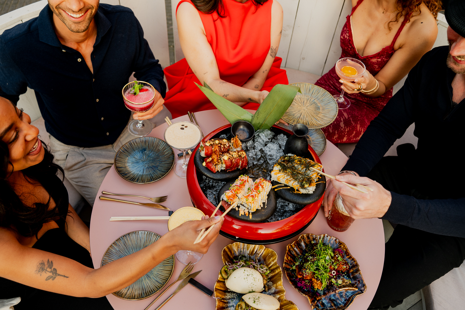 Gasten delen sushi, oesters en cocktails aan een volle tafel bij Miss Johnsen
